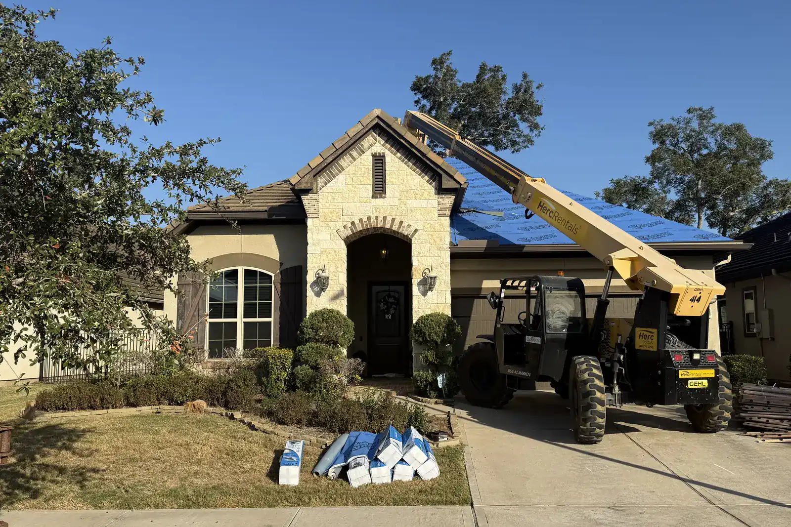 Roofing materials and lift equipment staged during active field work.